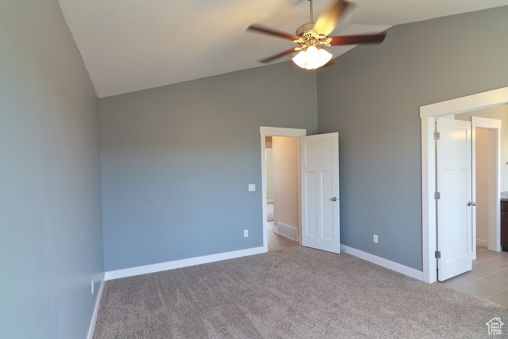Empty room with high vaulted ceiling, ceiling fan, and light colored carpet