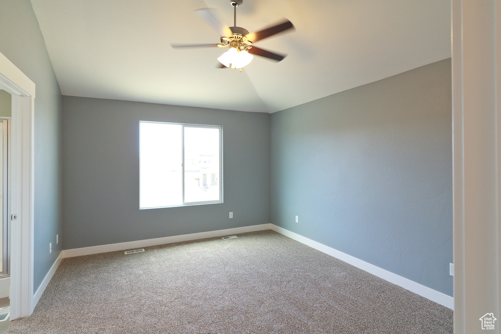 Unfurnished room featuring ceiling fan, vaulted ceiling, and light colored carpet