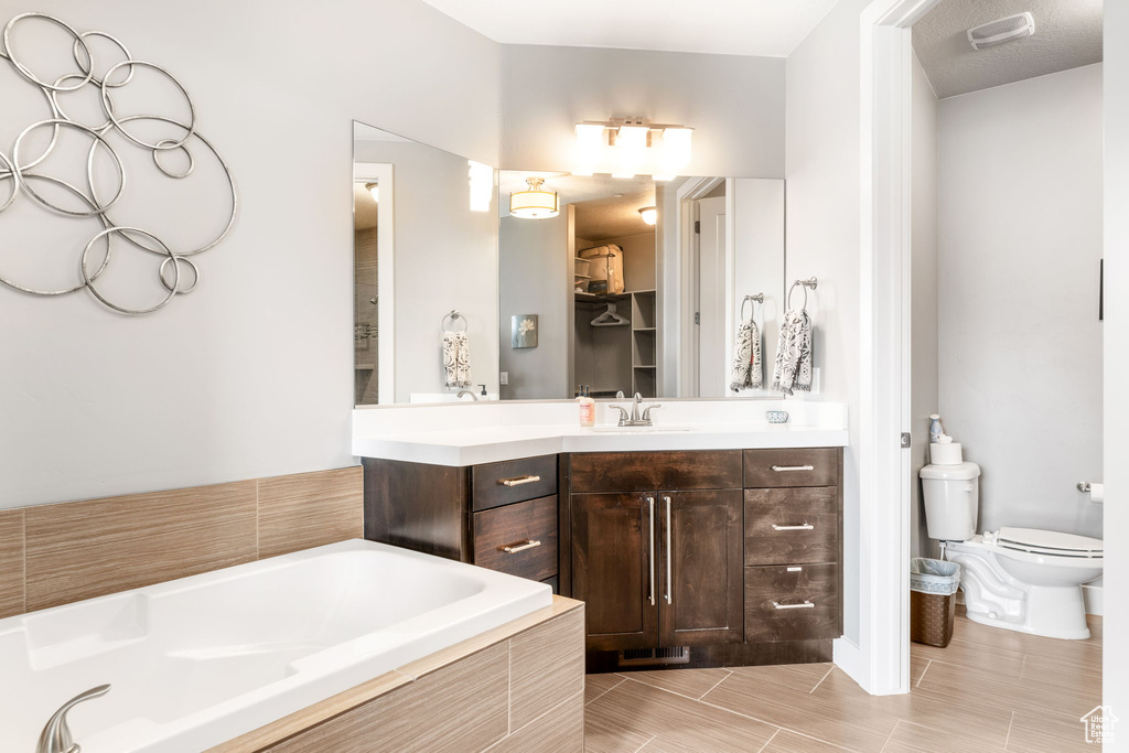 Bathroom with vanity, tile flooring, toilet, and tiled tub