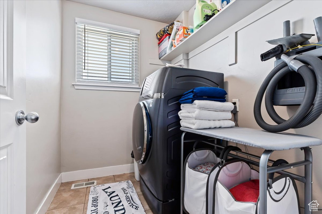 Clothes washing area featuring light tile floors and washing machine and clothes dryer