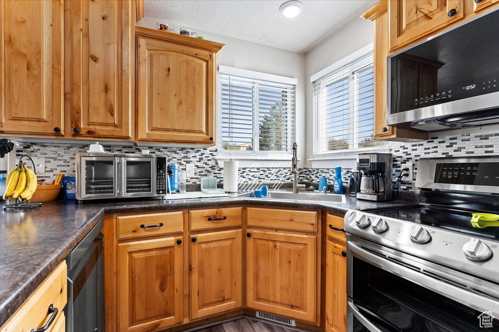 Kitchen featuring backsplash, stainless steel appliances, sink, and wine cooler
