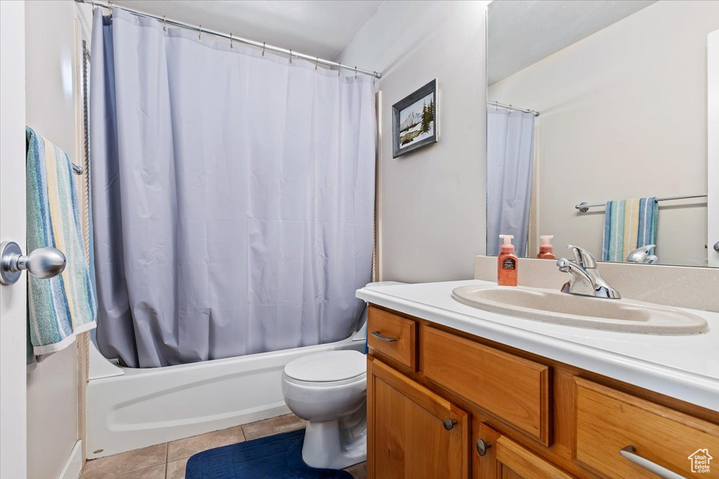 Full bathroom featuring toilet, vanity with extensive cabinet space, shower / tub combo with curtain, and tile floors