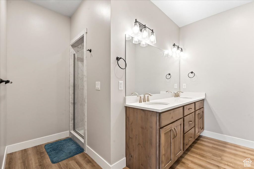 Bathroom with an enclosed shower, double vanity, and hardwood / wood-style flooring