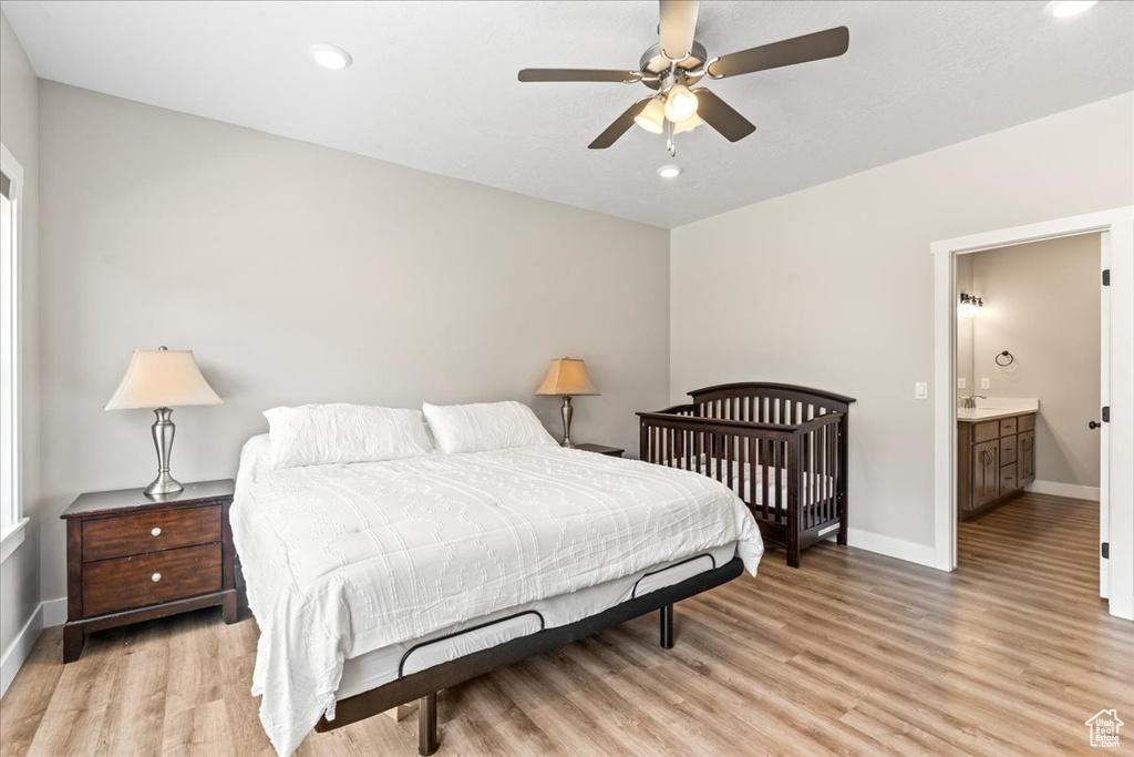 Bedroom with ceiling fan, ensuite bathroom, and light hardwood / wood-style flooring