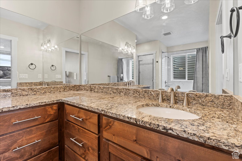 Bathroom with double sink, a chandelier, and vanity with extensive cabinet space