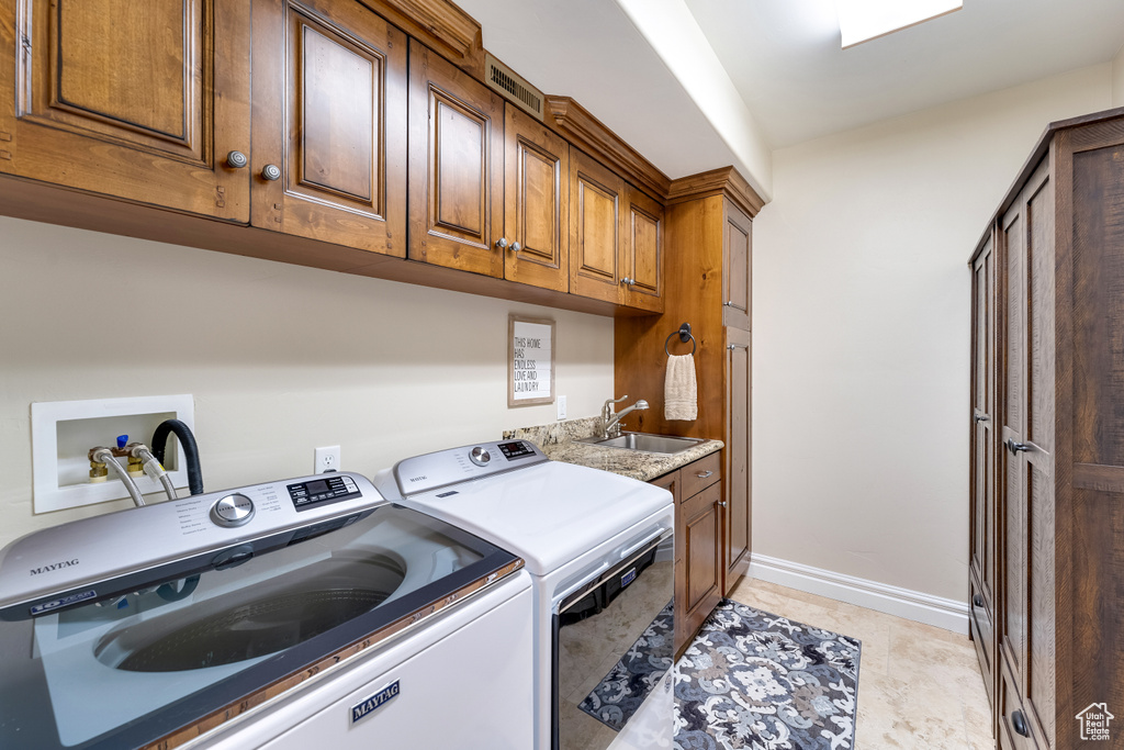 Washroom featuring washer hookup, sink, light tile floors, washing machine and clothes dryer, and cabinets