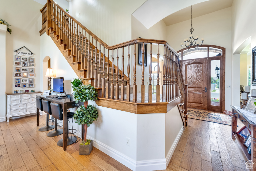 Entrance foyer featuring a high ceiling, a notable chandelier, and light hardwood / wood-style flooring