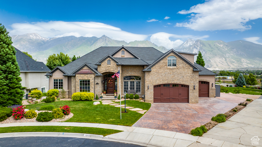 French country style house with a front lawn, a mountain view, and a garage