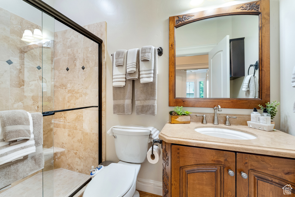 Bathroom featuring crown molding, a shower with shower door, oversized vanity, and toilet