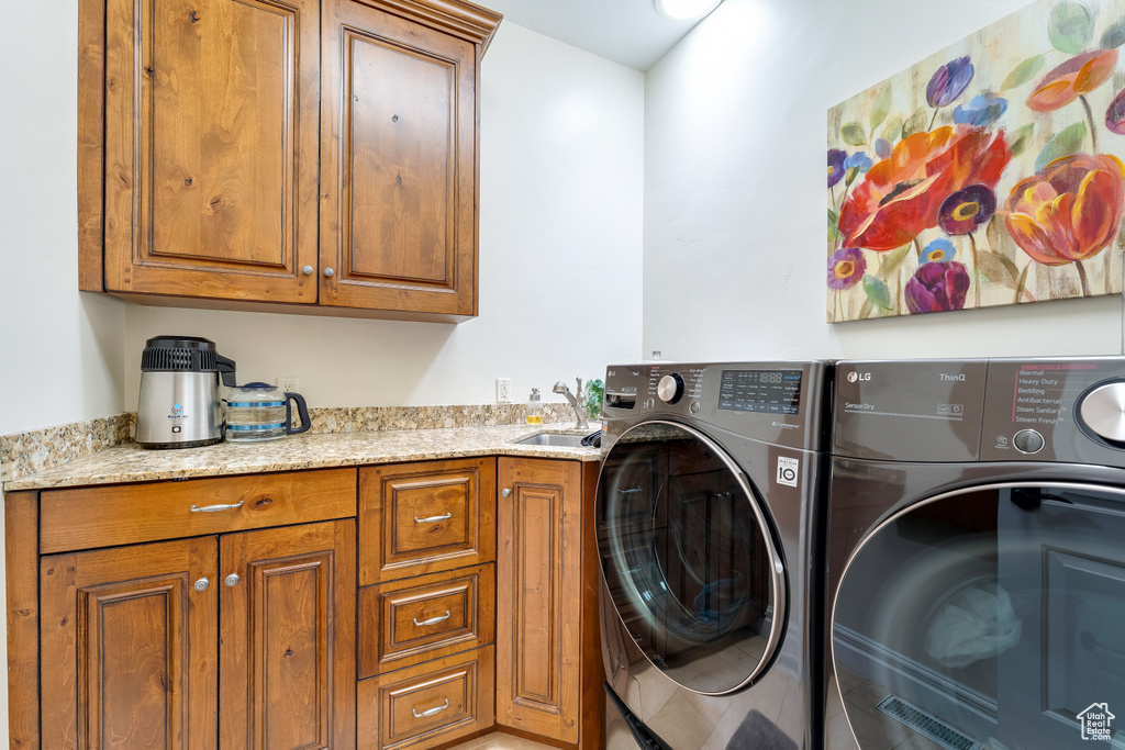 Laundry area with cabinets, separate washer and dryer, and sink