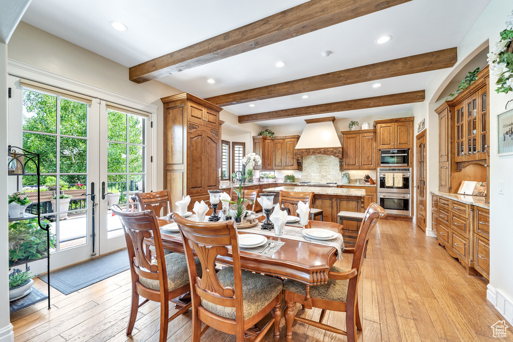 Dining room with beam ceiling, french doors, and light hardwood / wood-style floors