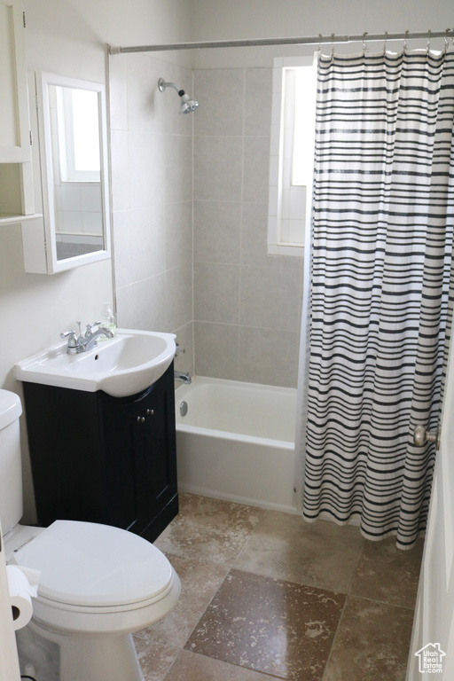 Full bathroom featuring toilet, shower / tub combo, vanity, and tile flooring