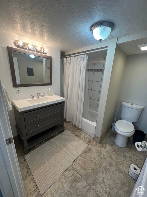 Full bathroom featuring toilet, large vanity, shower / bath combo with shower curtain, a textured ceiling, and tile floors