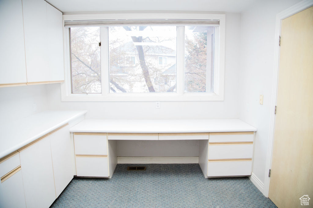 Unfurnished office featuring light colored carpet and built in desk