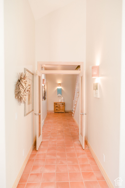 Hall with light tile flooring and lofted ceiling