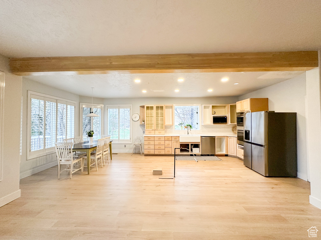 Kitchen featuring appliances with stainless steel finishes, beam ceiling, light brown cabinetry, and light wood-type flooring