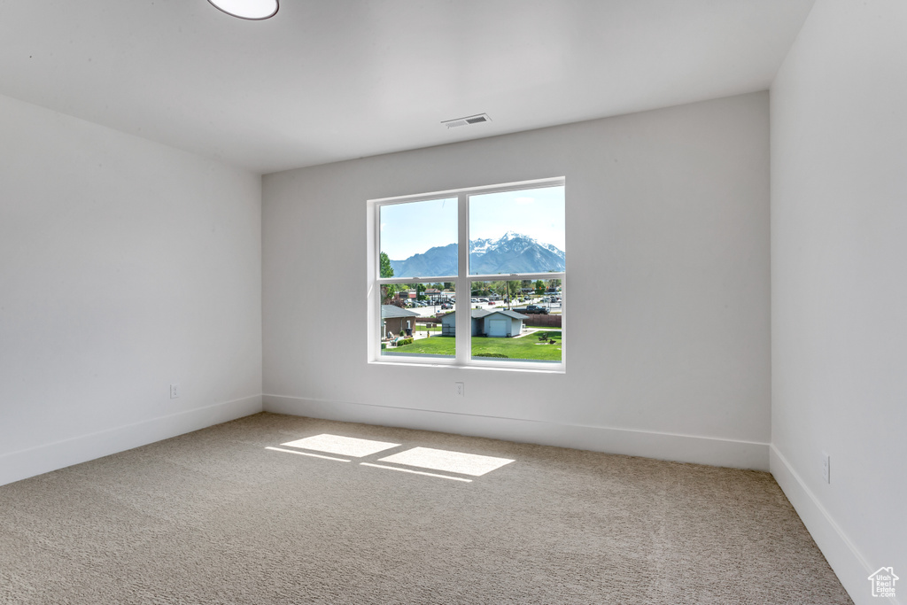 Unfurnished room featuring a mountain view and light colored carpet