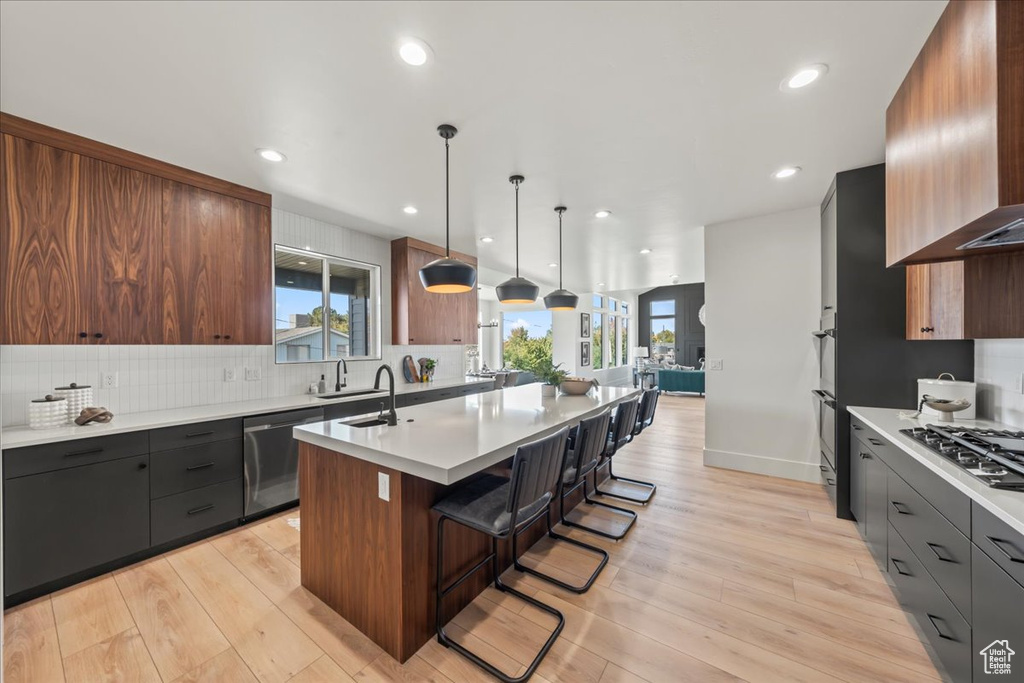 Kitchen featuring a kitchen breakfast bar, light hardwood / wood-style flooring, tasteful backsplash, and stainless steel appliances