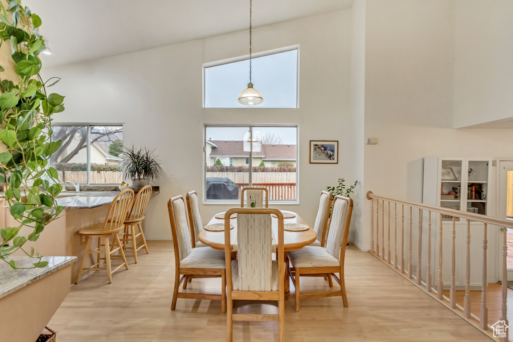Dining room with a towering ceiling and light hardwood / wood-style flooring