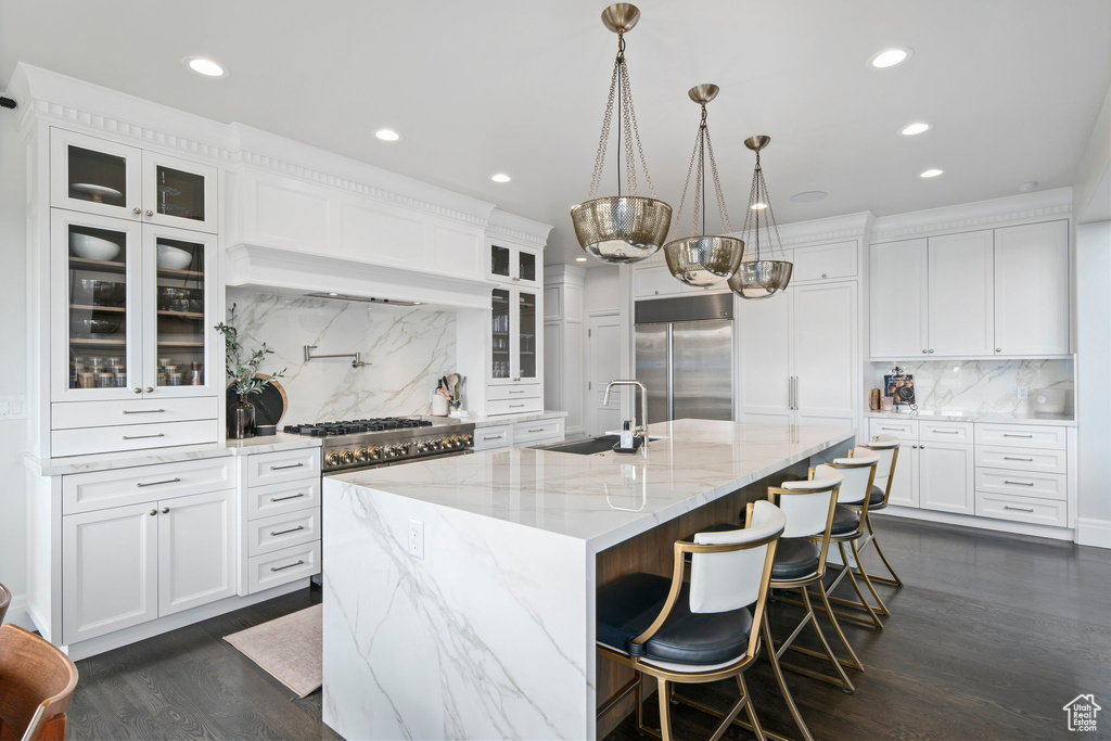 Kitchen featuring hanging light fixtures, dark hardwood / wood-style floors, appliances with stainless steel finishes, sink, and tasteful backsplash