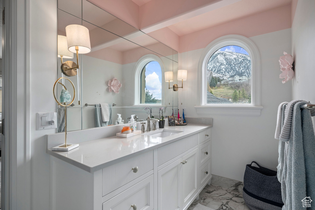 Bathroom with a healthy amount of sunlight, vanity with extensive cabinet space, and tile flooring
