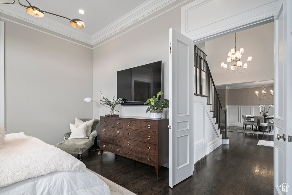 Bedroom with ornamental molding, dark hardwood / wood-style floors, and an inviting chandelier