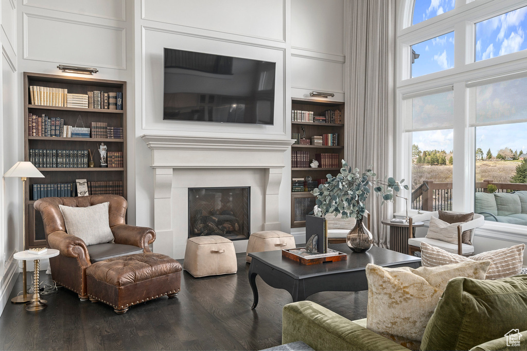 Living room featuring built in features, a wealth of natural light, and dark hardwood / wood-style flooring
