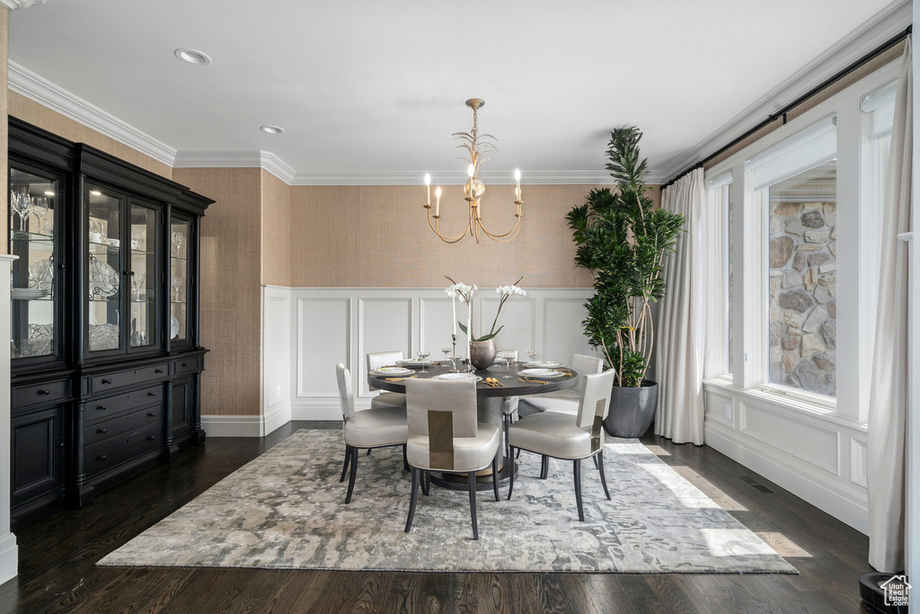 Dining area with crown molding, an inviting chandelier, and dark hardwood / wood-style flooring