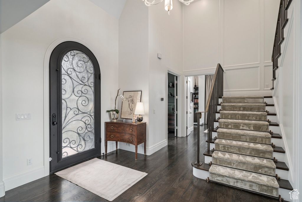 Entrance foyer with a notable chandelier, high vaulted ceiling, and dark hardwood / wood-style flooring