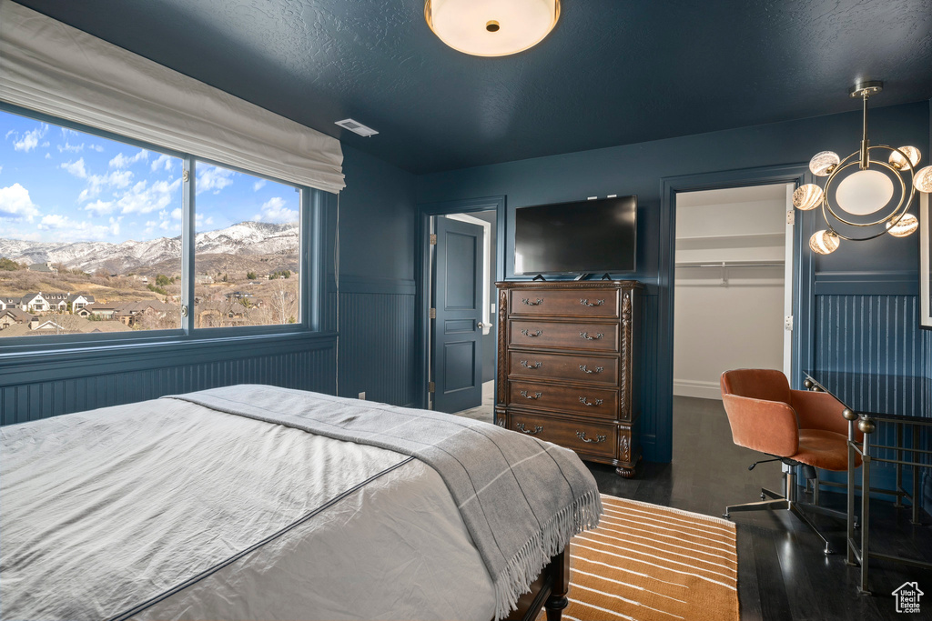 Bedroom with a mountain view, an inviting chandelier, a closet, and dark wood-type flooring