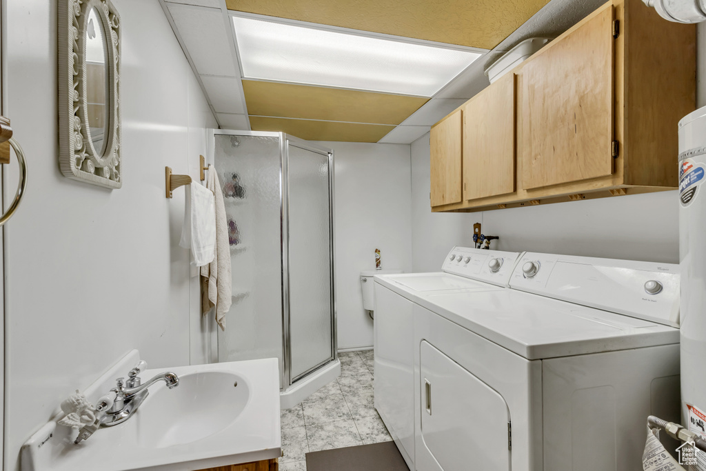 Washroom featuring separate washer and dryer, sink, and light tile floors