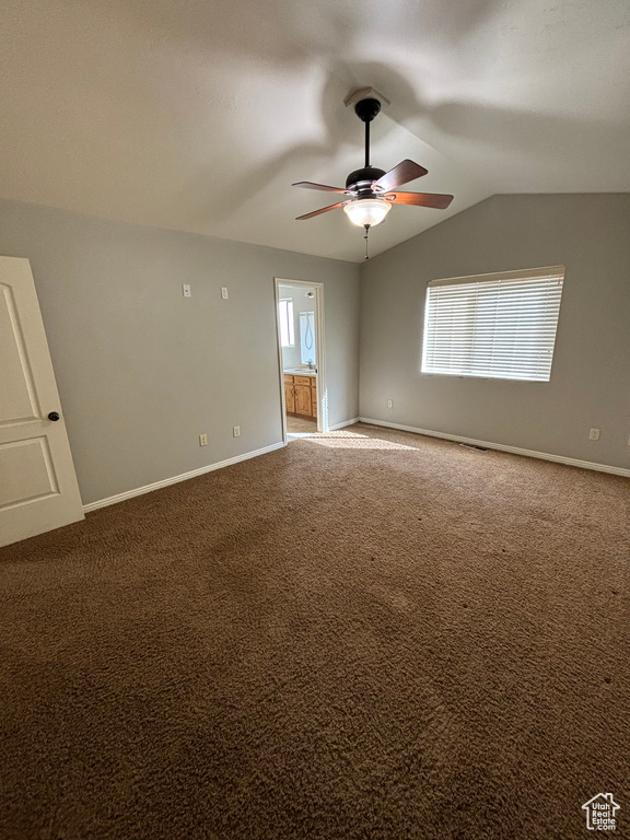 Carpeted spare room featuring plenty of natural light, ceiling fan, and lofted ceiling
