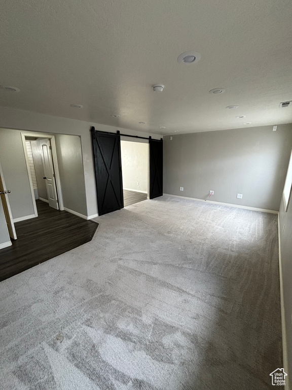 Unfurnished room featuring a barn door and carpet flooring