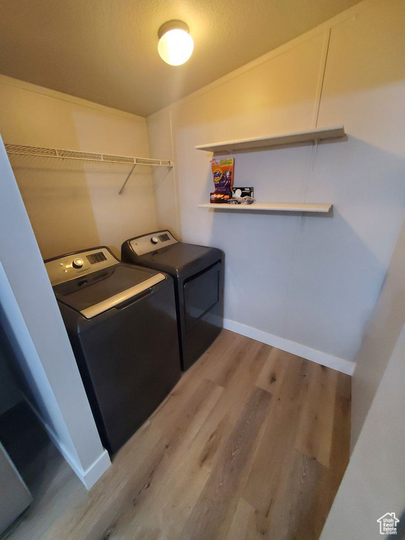 Laundry area with light hardwood / wood-style floors and washer and dryer