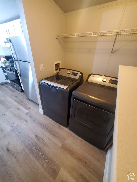 Laundry room featuring washer hookup, washer and clothes dryer, crown molding, and light hardwood / wood-style floors