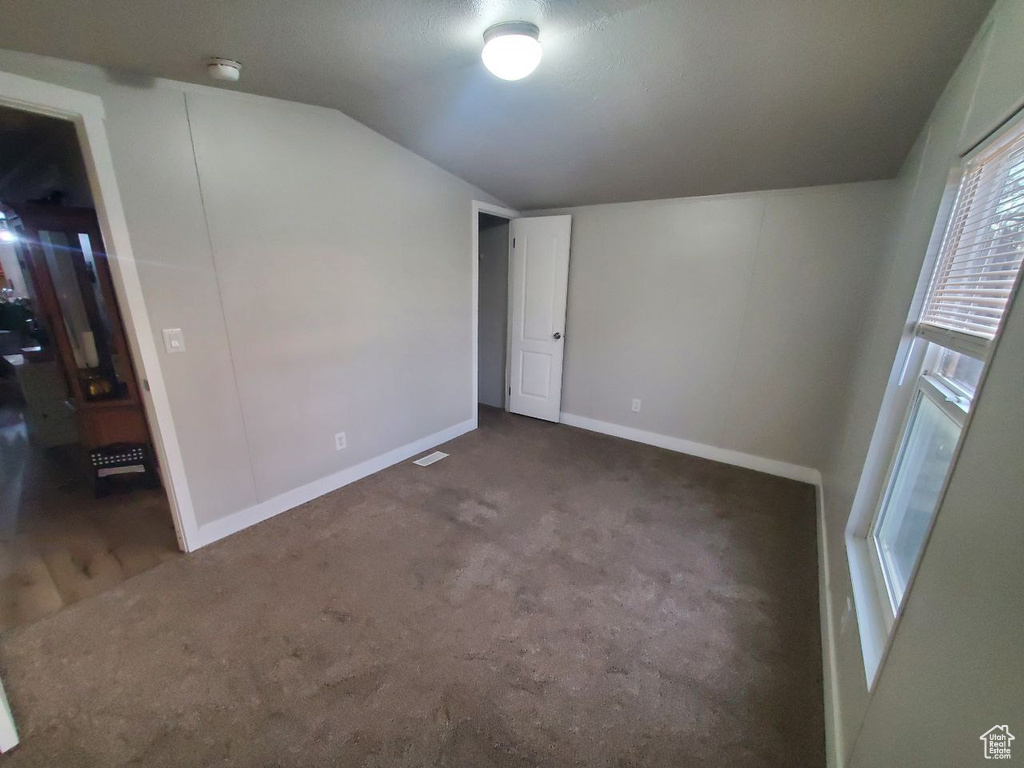 Carpeted empty room with vaulted ceiling