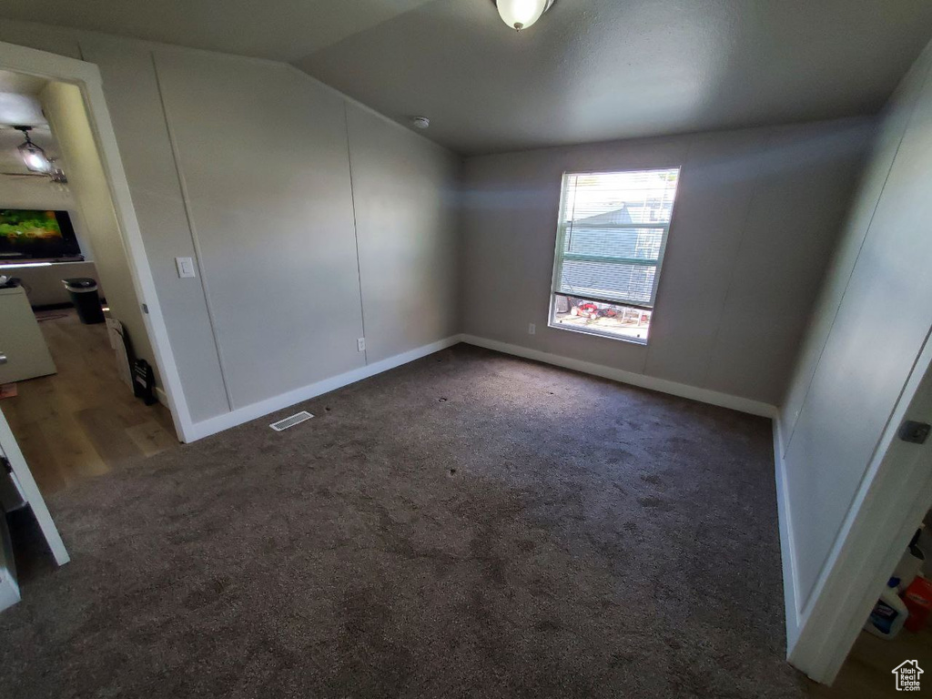 Spare room with carpet floors and vaulted ceiling