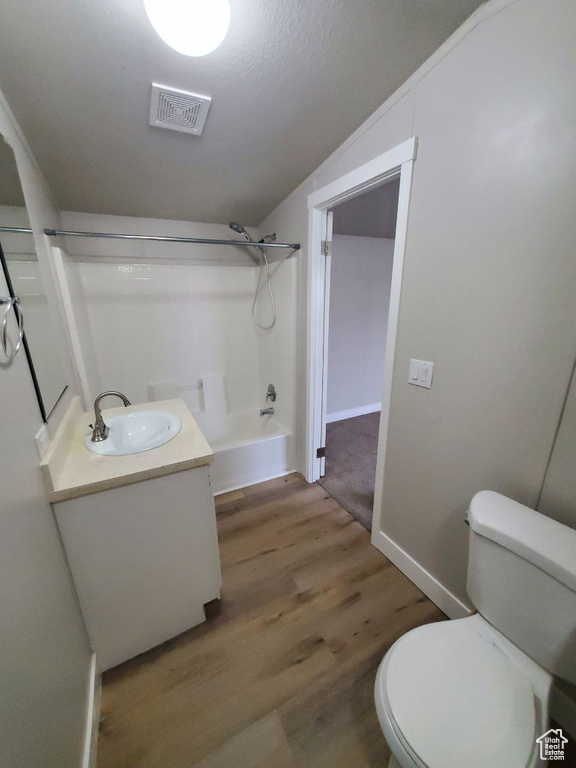 Full bathroom with toilet, shower / bath combination, wood-type flooring, vaulted ceiling, and vanity