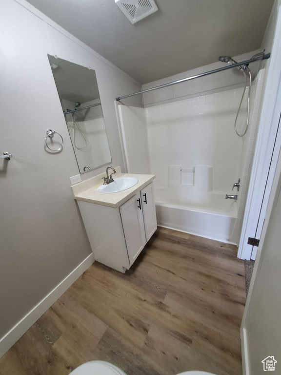 Bathroom featuring hardwood / wood-style floors, large vanity, and shower / washtub combination