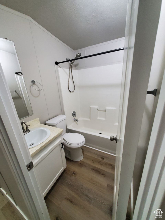 Full bathroom featuring vanity, a textured ceiling, shower / washtub combination, toilet, and hardwood / wood-style flooring