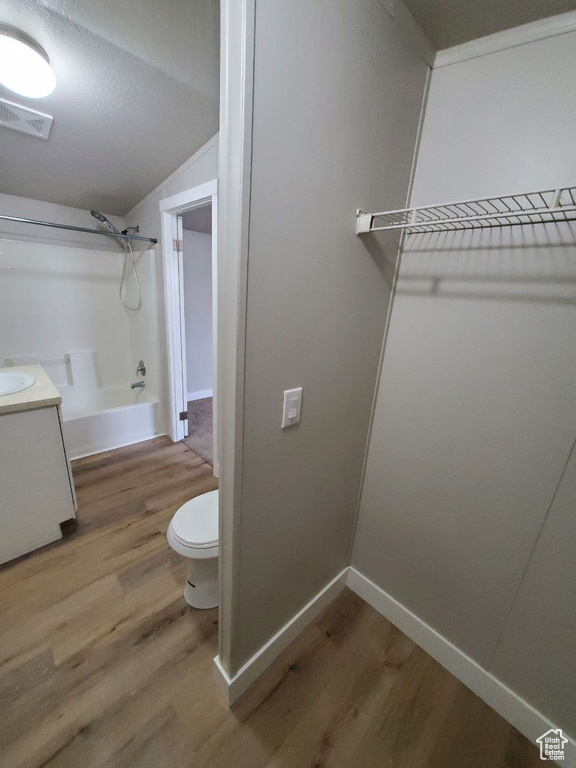 Interior space featuring vanity, toilet, shower / washtub combination, and hardwood / wood-style flooring