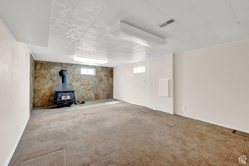 Unfurnished living room with carpet floors and a wood stove