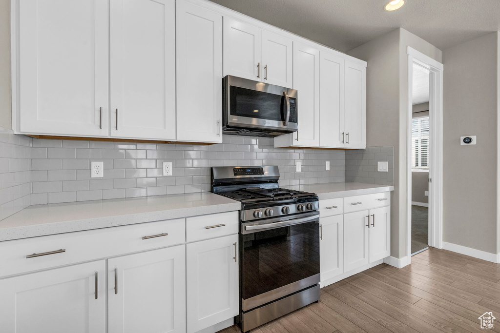 Kitchen featuring light hardwood / wood-style floors, appliances with stainless steel finishes, and white cabinetry