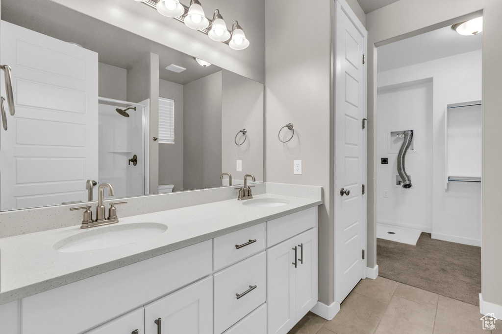 Bathroom with oversized vanity, dual sinks, walk in shower, and tile flooring