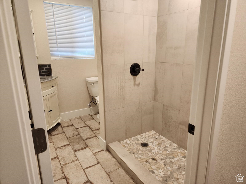 Bathroom featuring toilet, vanity, and tiled shower