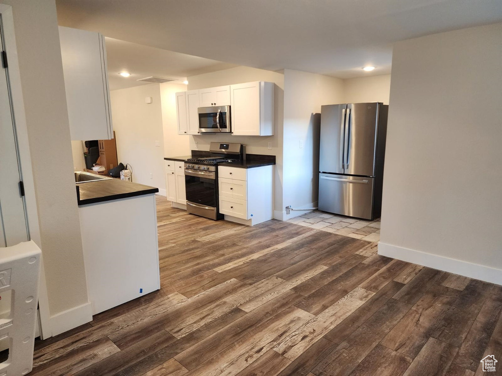 Kitchen featuring white cabinets, hardwood / wood-style flooring, and appliances with stainless steel finishes