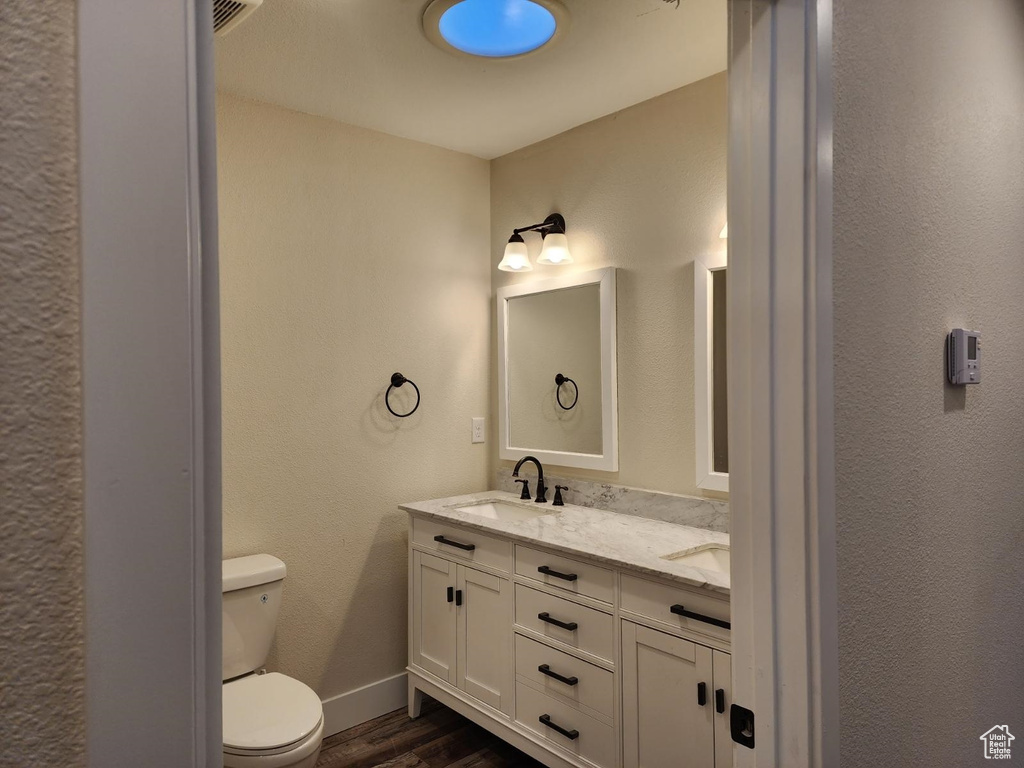 Bathroom with toilet, double vanity, and hardwood / wood-style flooring