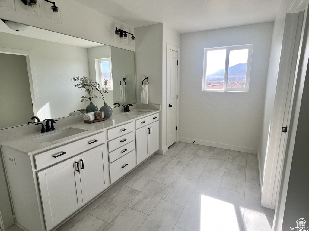 Bathroom featuring double sink vanity, tile flooring, and a healthy amount of sunlight