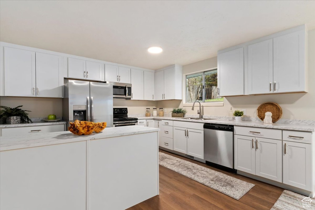 Kitchen with white cabinets, appliances with stainless steel finishes, and light stone counters