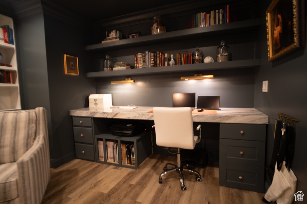 Office area with light hardwood / wood-style floors, built in shelves, and built in desk
